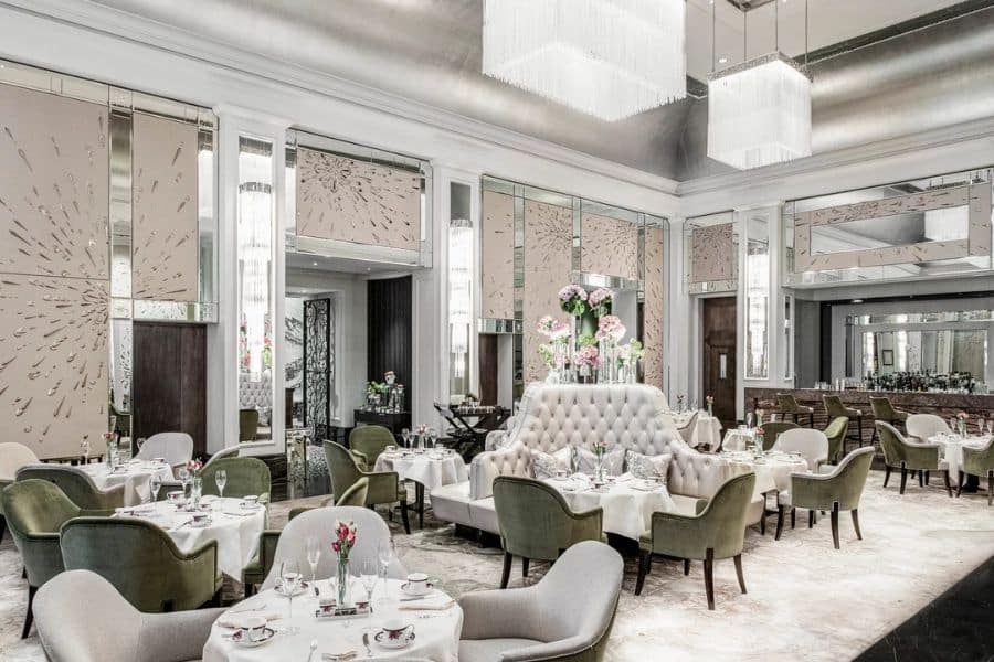 Bright and elegant hotel dining room with white tablecloths, pastel chairs, and mirrored walls — a modern yet classic example of European Hotels Where Famous Writers Lived.