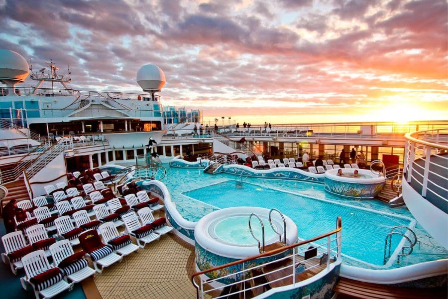 Cruise ship pool deck at sunset with lounge chairs and hot tubs, highlighting how not booking amenities early can be one of the Mistakes To Avoid On Your Next Cruise.