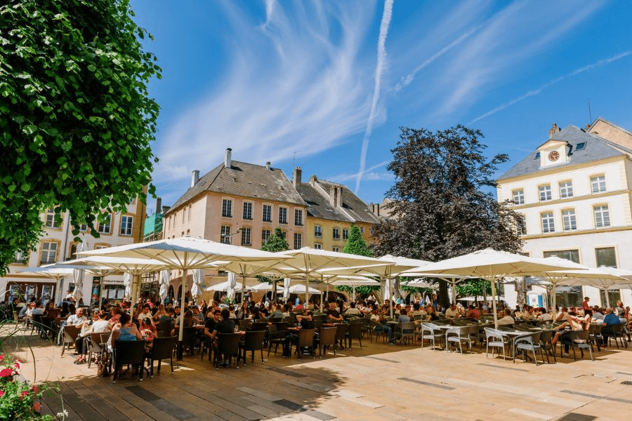 An outdoor square in France with lots of people sitting in cafes