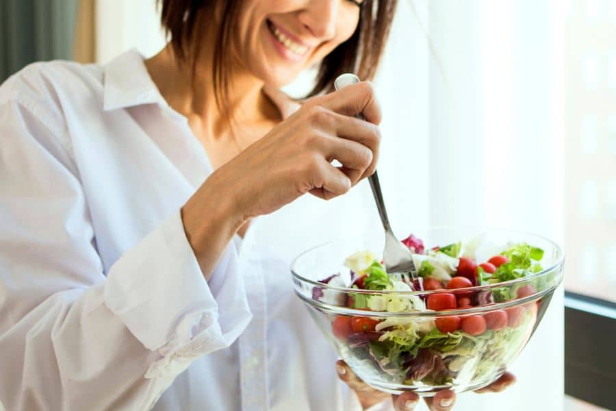 Woman in a white shirt eating a salad