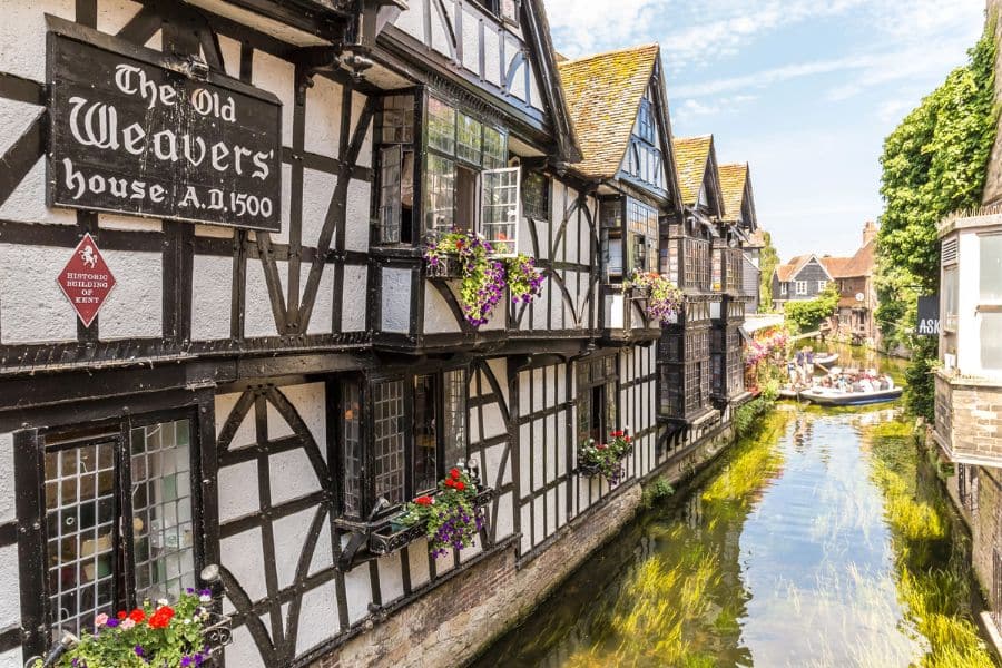 Half timbered medieval buildings overlooking a narrow canal with small boats highlighting charming European hotspots.