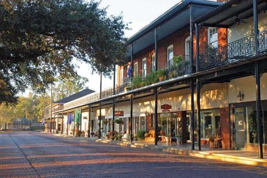Covered sidewalk with wrought iron balconies and local shops in a quaint Southern setting of historic American towns.
