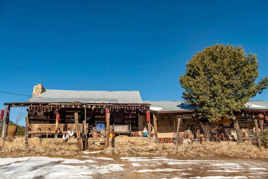 Rustic wooden homestead with a tin roof and front porch set against a rural landscape in historic American towns.