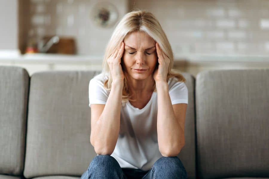 Woman sat on a sofa with her head in her hands