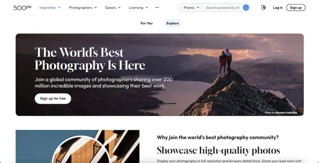 Screenshot of the 500px homepage with a mountain landscape banner and two people standing on a rocky peak at sunset. Visible text includes "500px" "Inspiration" "Photographers" "Quests" "Licensing" "For You" "Explore" "The World’s Best Photography Is Here" "Join a global community of photographers sharing over 200 million incredible images and showcasing their best work." "Sign up for free" "Photo by Silvestrs Indricāns" "Why join the world’s best photography community?" and "Showcase high quality photos."