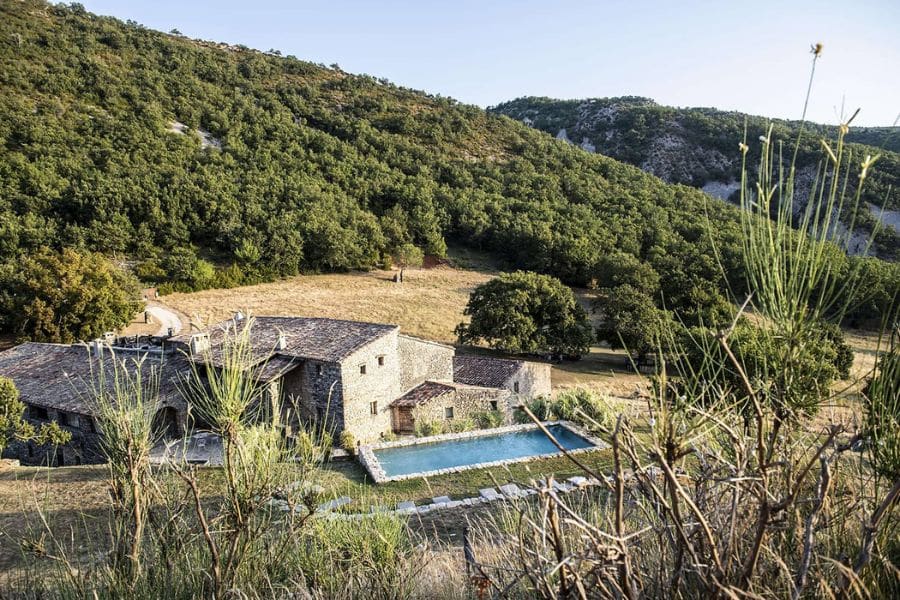 Rustic stone farmhouse with a pool surrounded by rolling green hills and forest close to European National Parks.
