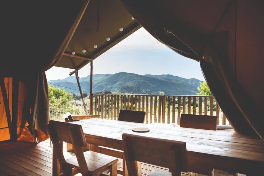 Glamping tent terrace with wooden table and mountain views offering unique stays near European National Parks.