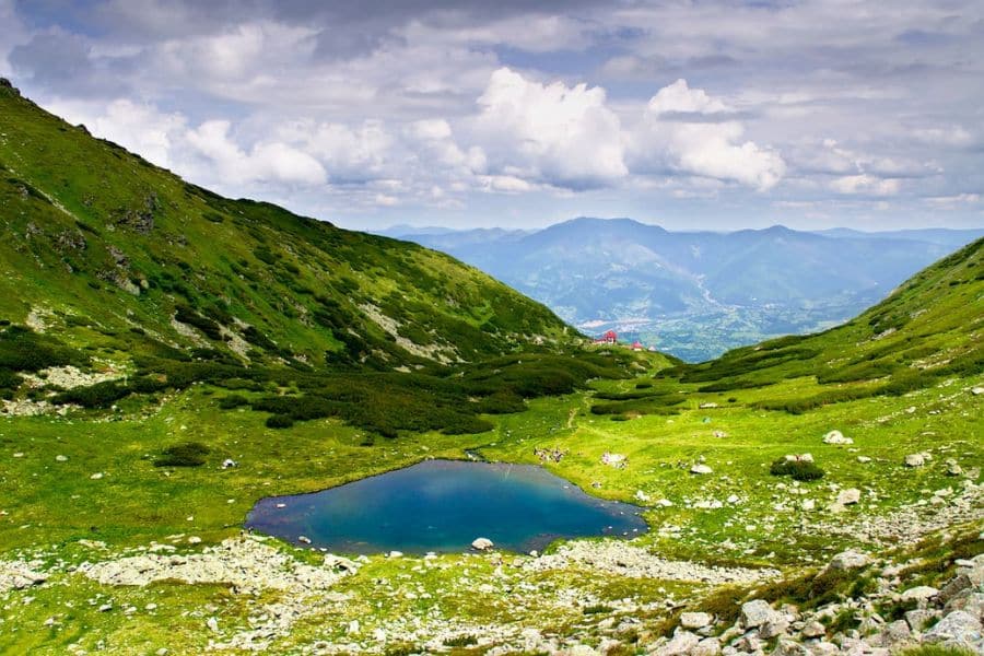 Small alpine lake nestled between green mountain slopes showcasing the natural beauty of European National Parks.