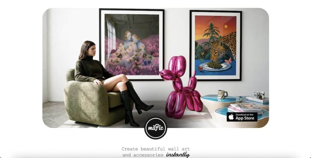 Interior promo scene with a woman seated in a textured green chair beside a shiny pink balloon dog sculpture and two framed art prints on the wall. Visible text includes "miPic" "Download on the App Store" and "Create beautiful wall art and accessories instantly."