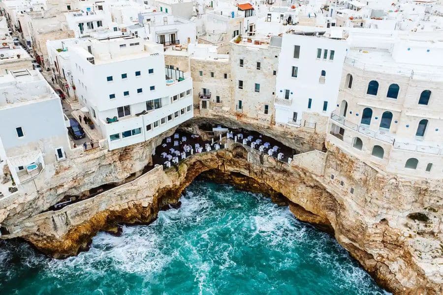 Coastal village built above crashing waves with restaurants tucked into seaside caves illustrating scenic villages in Italy.
