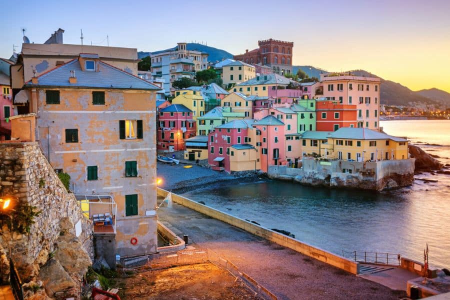 Colorful waterfront houses at sunset along a small harbor reflecting charming fishing villages in Italy.