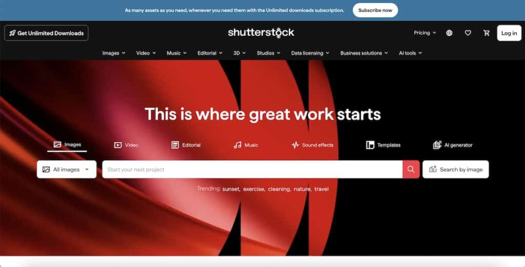 Screenshot of the Shutterstock homepage with a bold red and black abstract background behind the main search bar. Visible text includes "As many assets as you need, whenever you need them with the Unlimited downloads subscription." "Subscribe now" "Get Unlimited Downloads" "shutterstock" "Pricing" "Log in" "Images" "Video" "Music" "Editorial" "3D" "Studios" "Data licensing" "Business solutions" "AI tools" "This is where great work starts" "Images" "Video" "Editorial" "Music" "Sound effects" "Templates" "AI generator" "All images" "Start your next project" "Search by image" and "Trending: sunset, exercise, cleaning, nature, travel."
