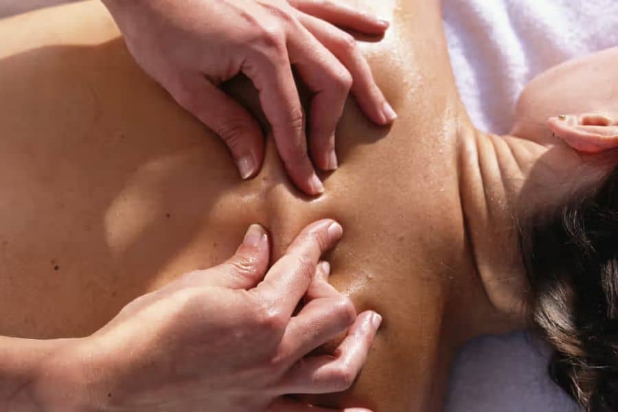 Close up of hands applying massage pressure to a person’s upper back and shoulder during a treatment session. This sciatica care image highlights hands on therapy used to relieve muscle tension and discomfort.