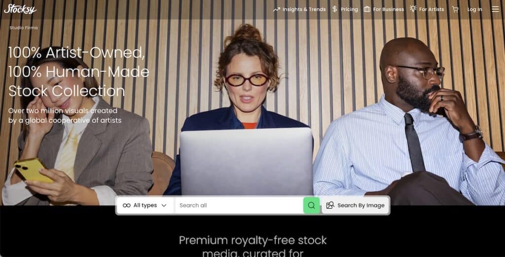 Screenshot of the Stocksy homepage showing three professionally dressed people seated against a wall of vertical wood slats, with the person in the center working on a laptop and the others looking at their phones or off to the side. Visible text includes "Stocksy" "Insights and Trends" "Pricing" "For Business" "For Artists" "Log In" "Studio Firma" "100% Artist-Owned, 100% Human-Made Stock Collection" "Over two million visuals created by a global cooperative of artists" "All types" "Search all" "Search By Image" and "Premium royalty-free stock media, curated for".