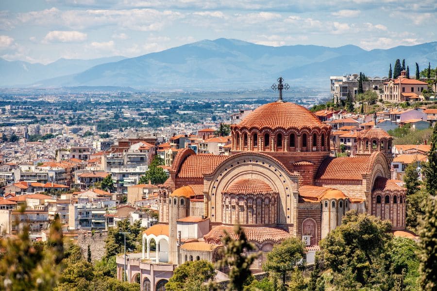 A large domed church with terracotta roofs overlooks a dense cityscape with mountains rising in the distance. This supports vacation destinations content by featuring historic architecture, urban views, and a dramatic mountain backdrop.