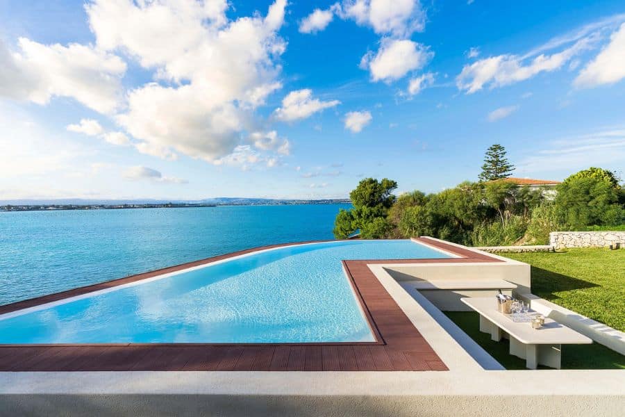 Modern infinity pool overlooking turquoise sea and coastal cliffs close to European National Parks.
