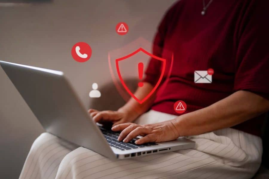 Person using a laptop with red security warning icons for calls messages and account alerts. The visual shows online risks connected to money scams.