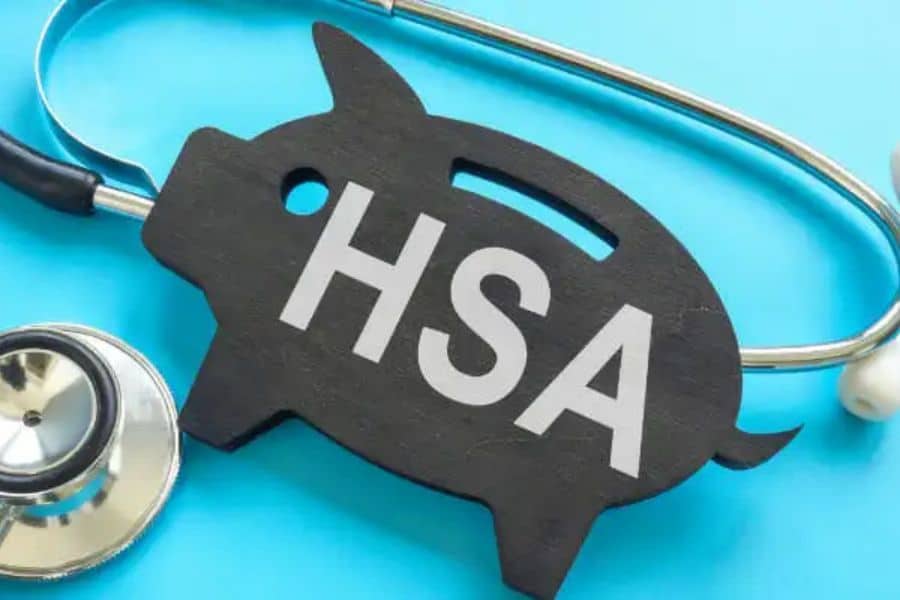A black piggy bank cutout with the letters "HSA" sits on a blue background beside a stethoscope. This is useful in retirement savings content because it connects health savings accounts with long term financial planning and future medical costs.