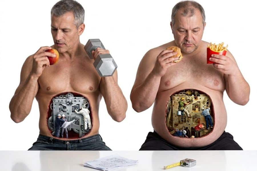 Two shirtless men compare food choices and body types with tiny construction scenes inside their stomachs. One eats an apple and holds a dumbbell while the other holds a burger and fries to show lifestyle habits that may speed up your metabolism.