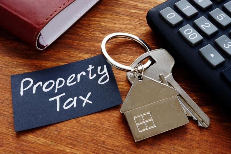 House shaped keychain beside a note that says "Property Tax" with a calculator nearby.
