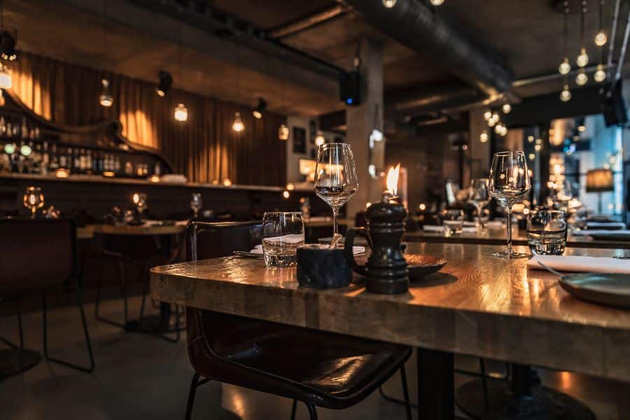 A dimly lit restaurant table is set with wine glasses. Water glasses. Napkins. And a small candle.