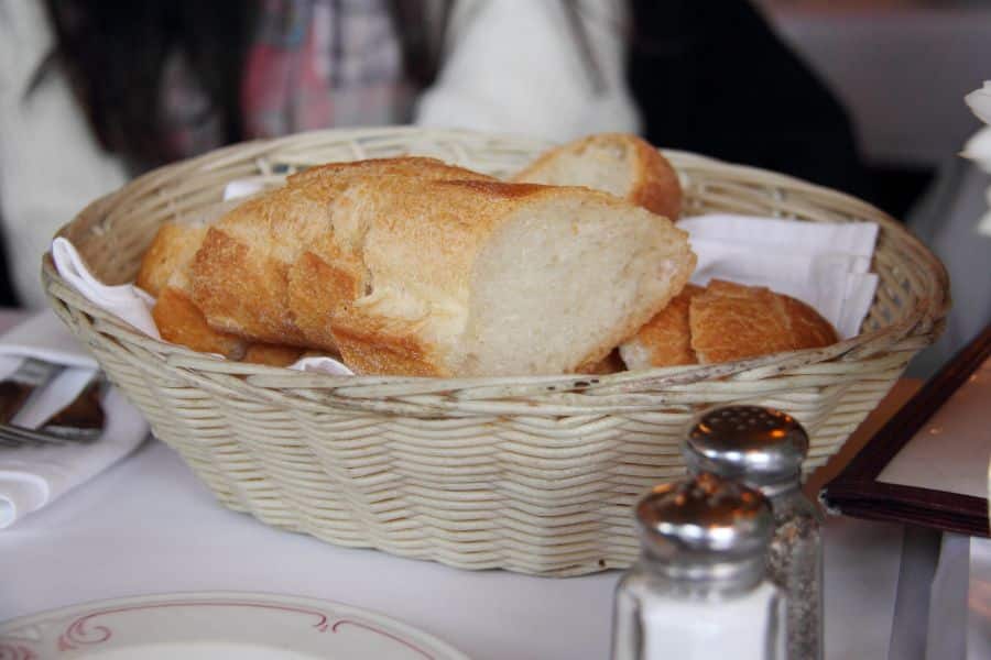 Sliced bread in a wicker basket on a restaurant table beside salt and pepper shakers.