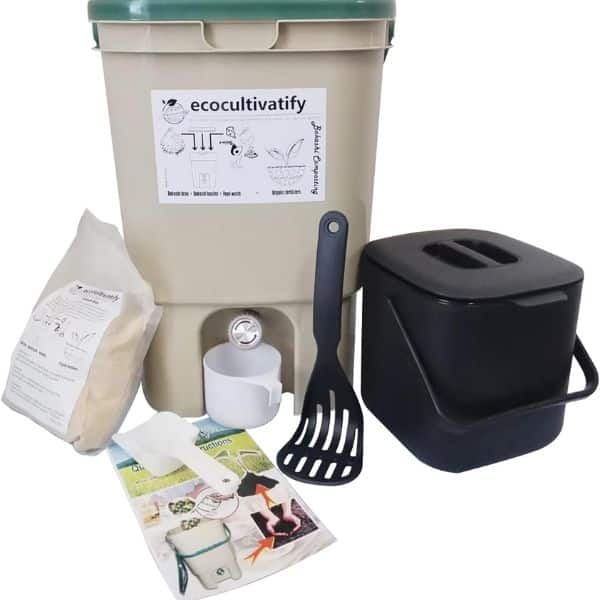 A home compost starter kit with a large lidded container. A small countertop bin. A bag of composting material. A scoop. A thermometer. A mixing tool. And printed instructions. The label on the large container reads "ecocultivafy".