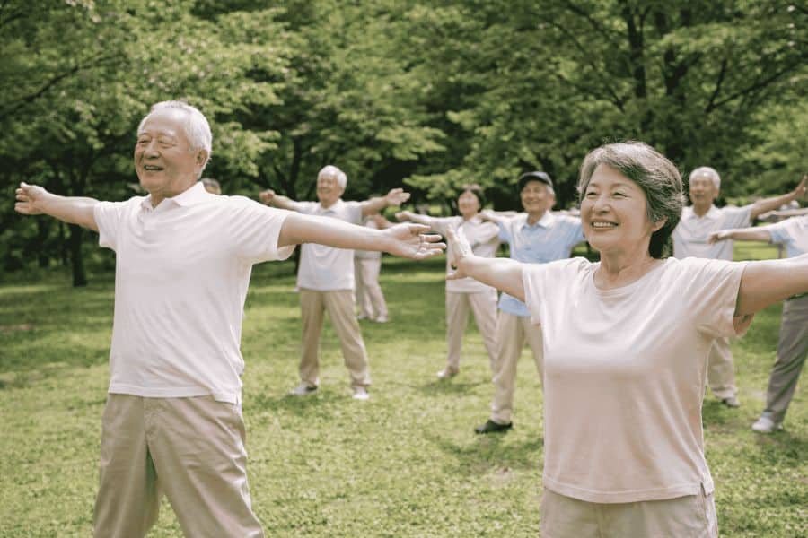 A group of people in a field with arms and legs wide doing Japanese core exercises