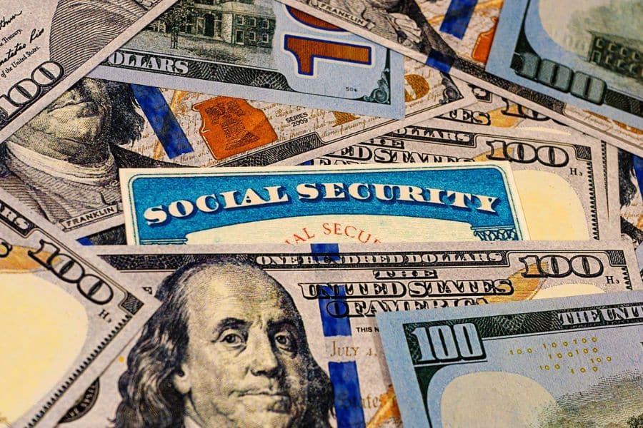 Lots of dollar bills spread out with the words social security in the middle