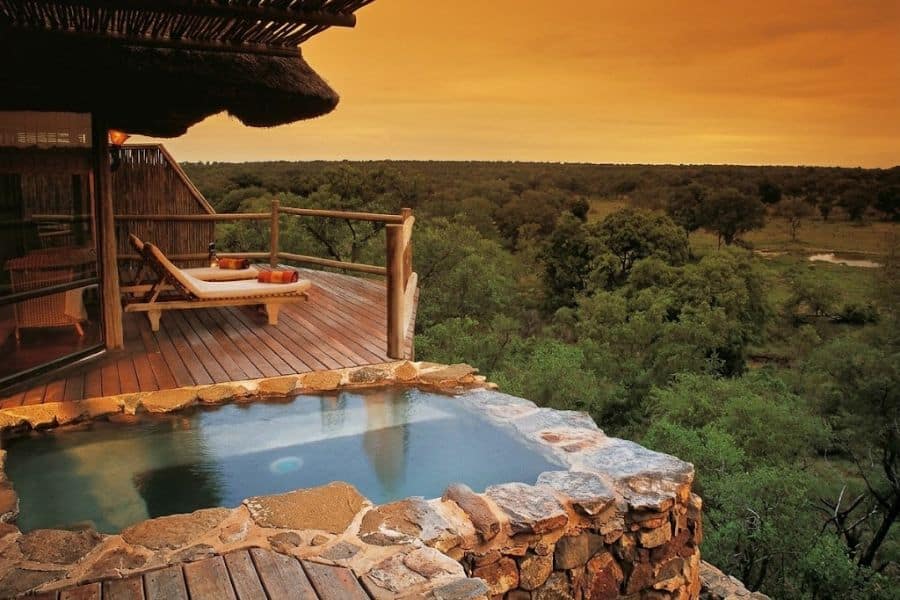 Sunset over the African safari land with a pool overlooking the landscape.