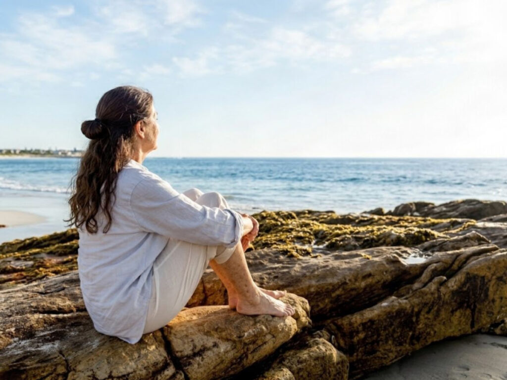 A woman in a white shirt staring out to sea thinking about planning your retirement